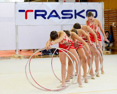 Krásné gymnastky s obručemi na sportovním vystoupení, reprezentující projekty a stavby společnosti T.