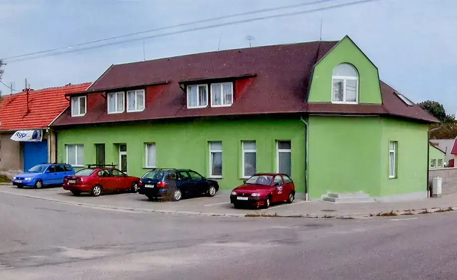 Moderní dům s pestrým nátěrem a parkovištěm v obci.