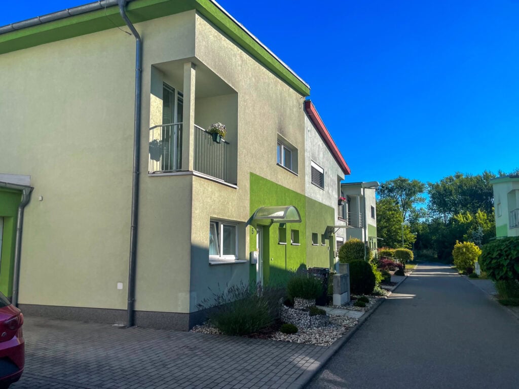 Moderní rodinný dům s zelenou fasádou a balkonem v Rousínově.