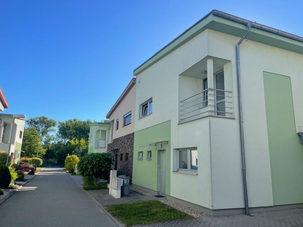Moderní rodinný dům v Rousínově s bílou fasádou a balkonem.